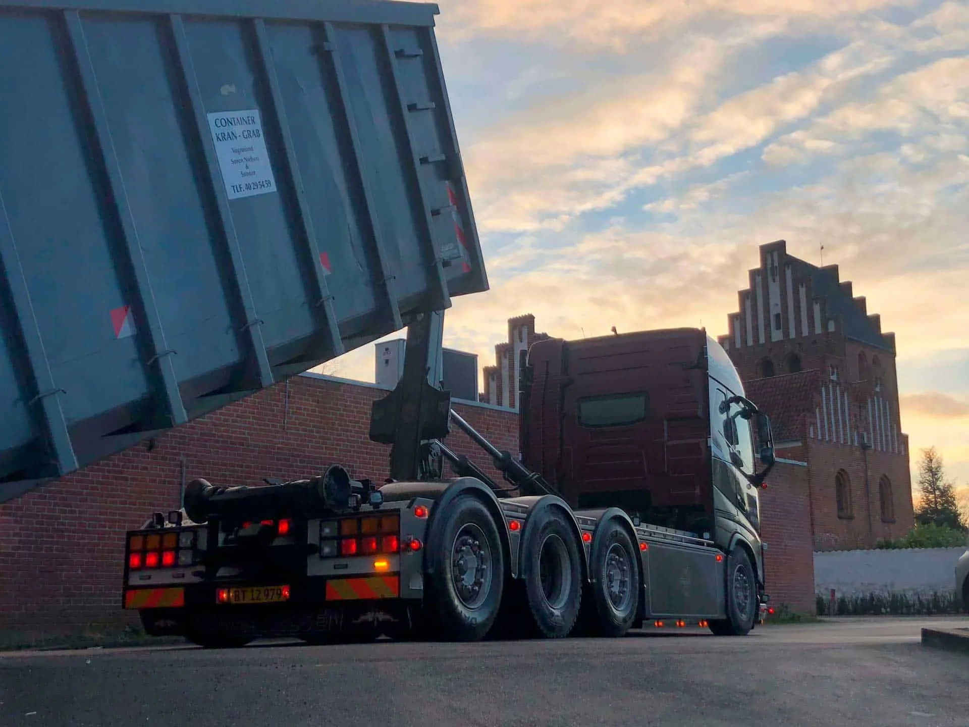 Volvo-kranbil fra VSN Gruppen sætter container af med kran i aftensol